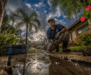 A NaturePest technician sealing foundation cracks during Florida rainy season inspection for palmetto bug prevention in Miami home.